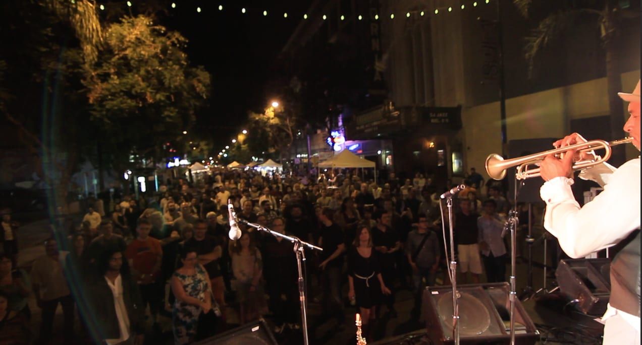 Doug Ellington performing to a packed street crowd under string lights at San Jose Jazz Summer Fest