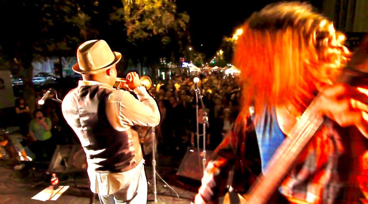 Doug Ellington playing trumpet on stage with his band before a night crowd